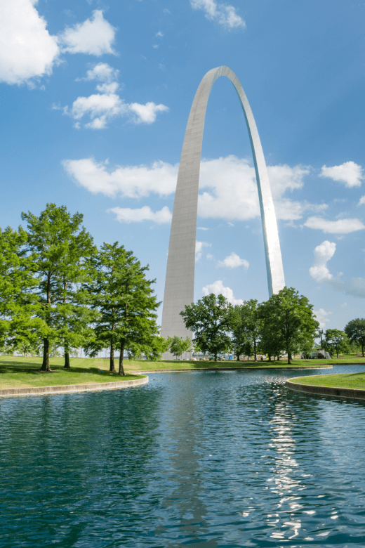The St Louis Gateway Arch in Missouri with the lake in front and the reflection in the water.