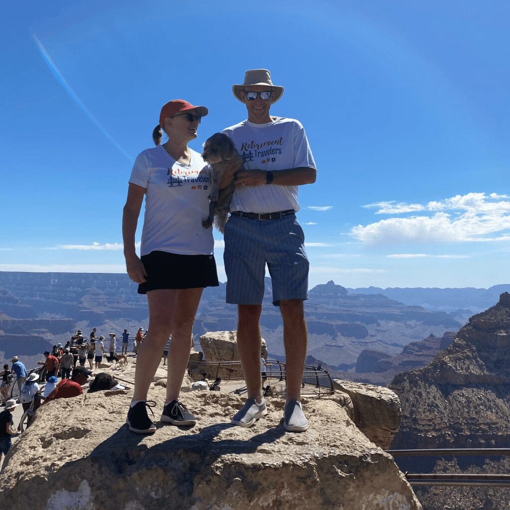 A man and woman holding a dog with the Grand Canyon in the background