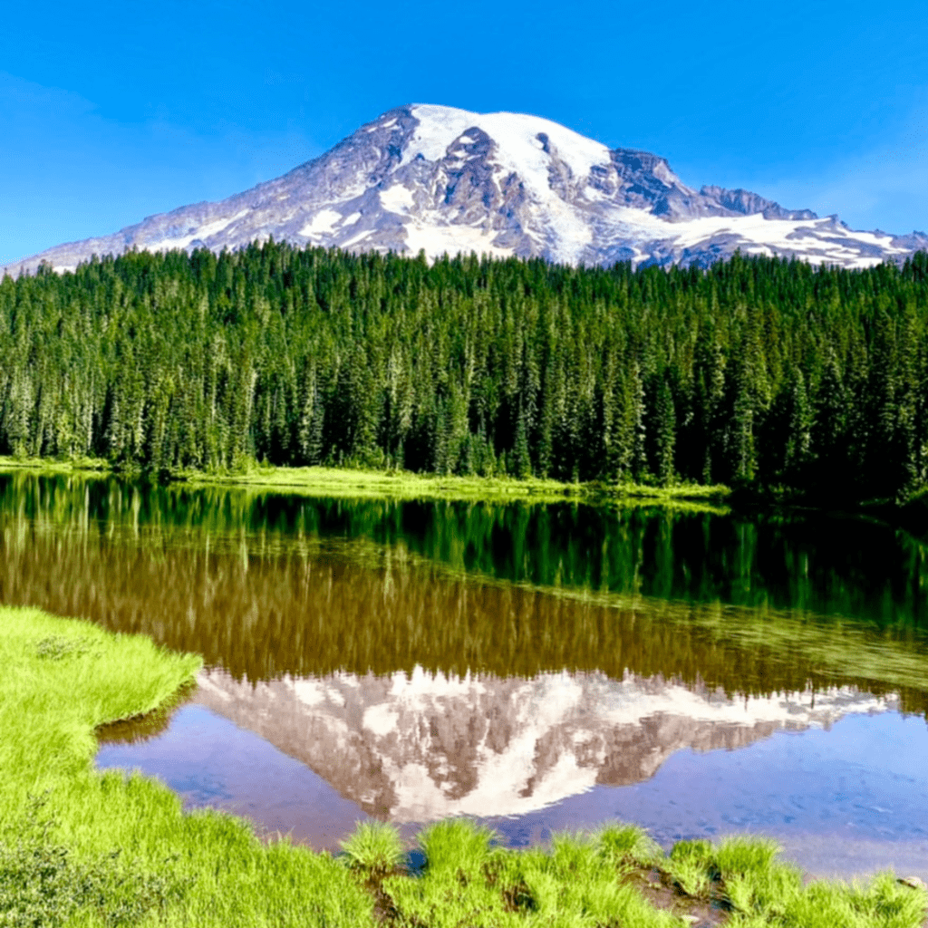 A snow-capped mountain being reflected in an alpine lake