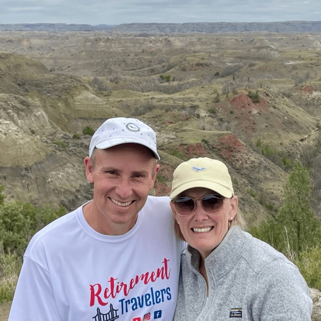 A man and woman with badlands of North Dakota in background