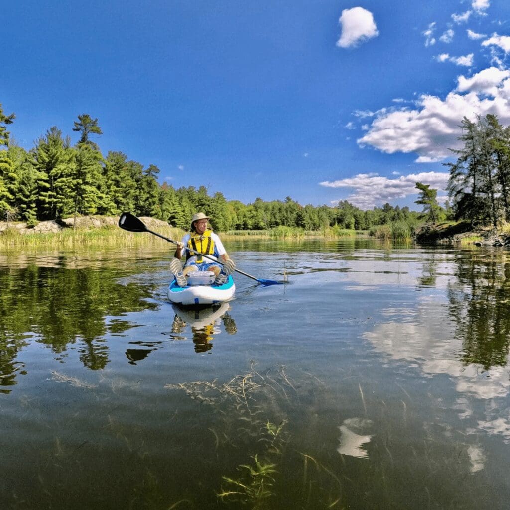 A man paddling on a paddleboard in a lake surrounded by trees