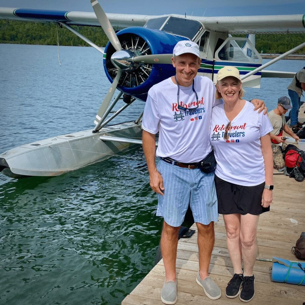 A man and woman standing on a dock by a seaplane