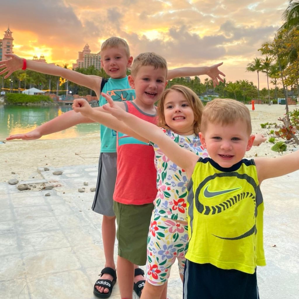 four children posing with arms out like airplane