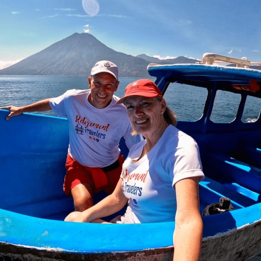 Woman and man in blue boat with volcano in background behind lake