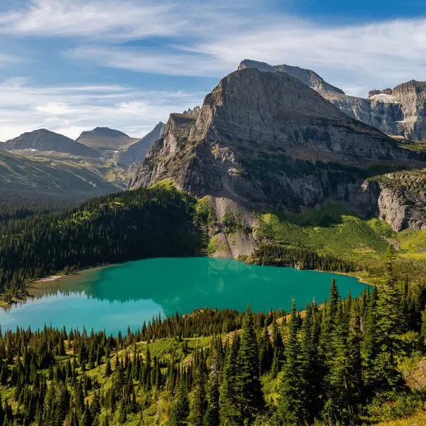 Teal colored lake surrounded by mountains in Glacier National Park in Montana