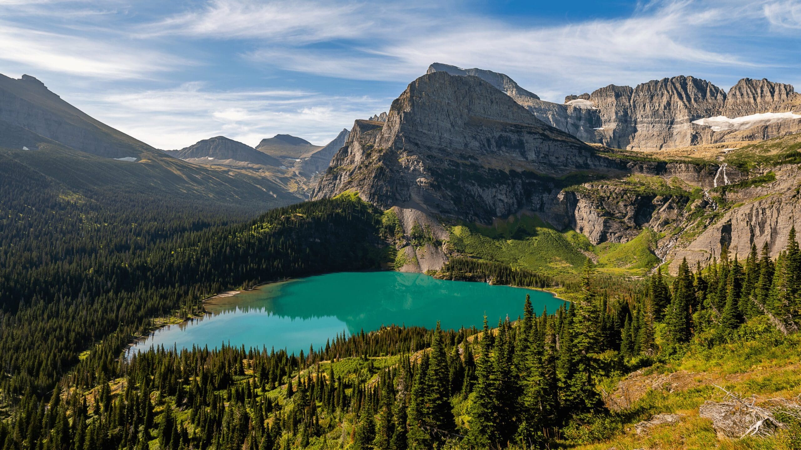 Teal colored lake surrounded by mountians