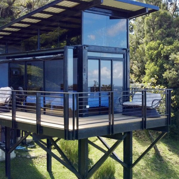 a container home on stilts looking out over rainforest
