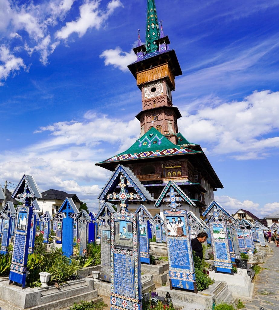 Romanian church surrounded by blue wooden tombstones that are handpainted
