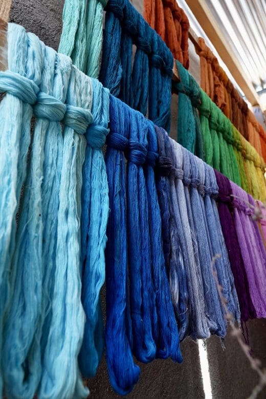 bunches of string hanging to dry after being dyed many colors