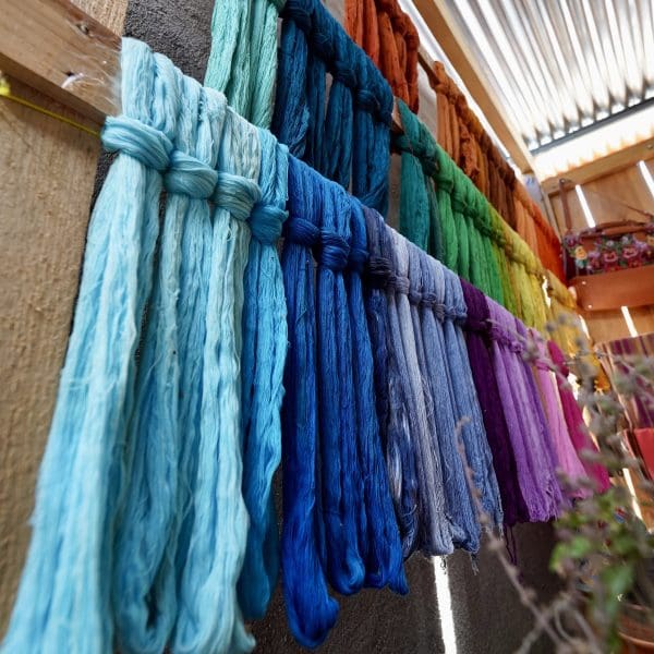 bunches of string hanging to dry after being dyed many colors