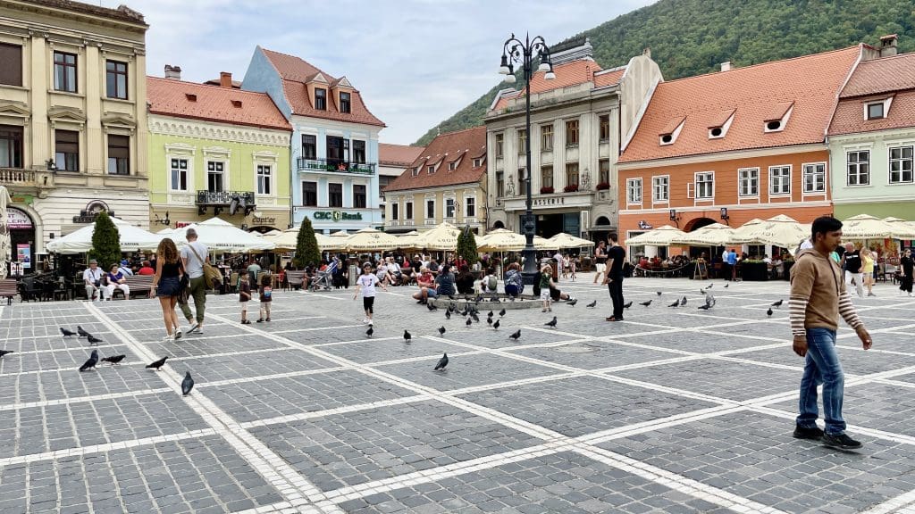 an open square with people walking and children playing with pigeons
