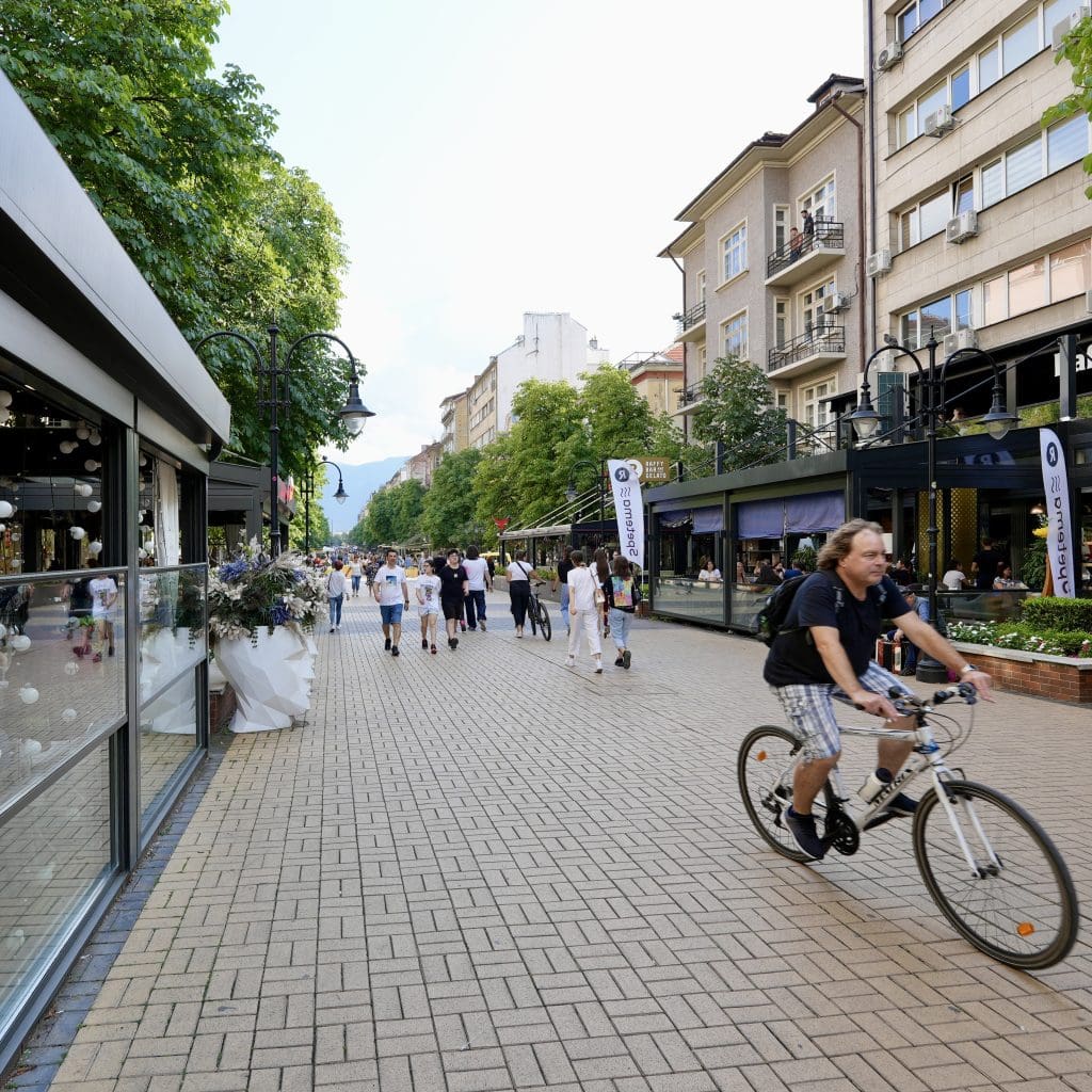 a view of the street with a biker and walkers