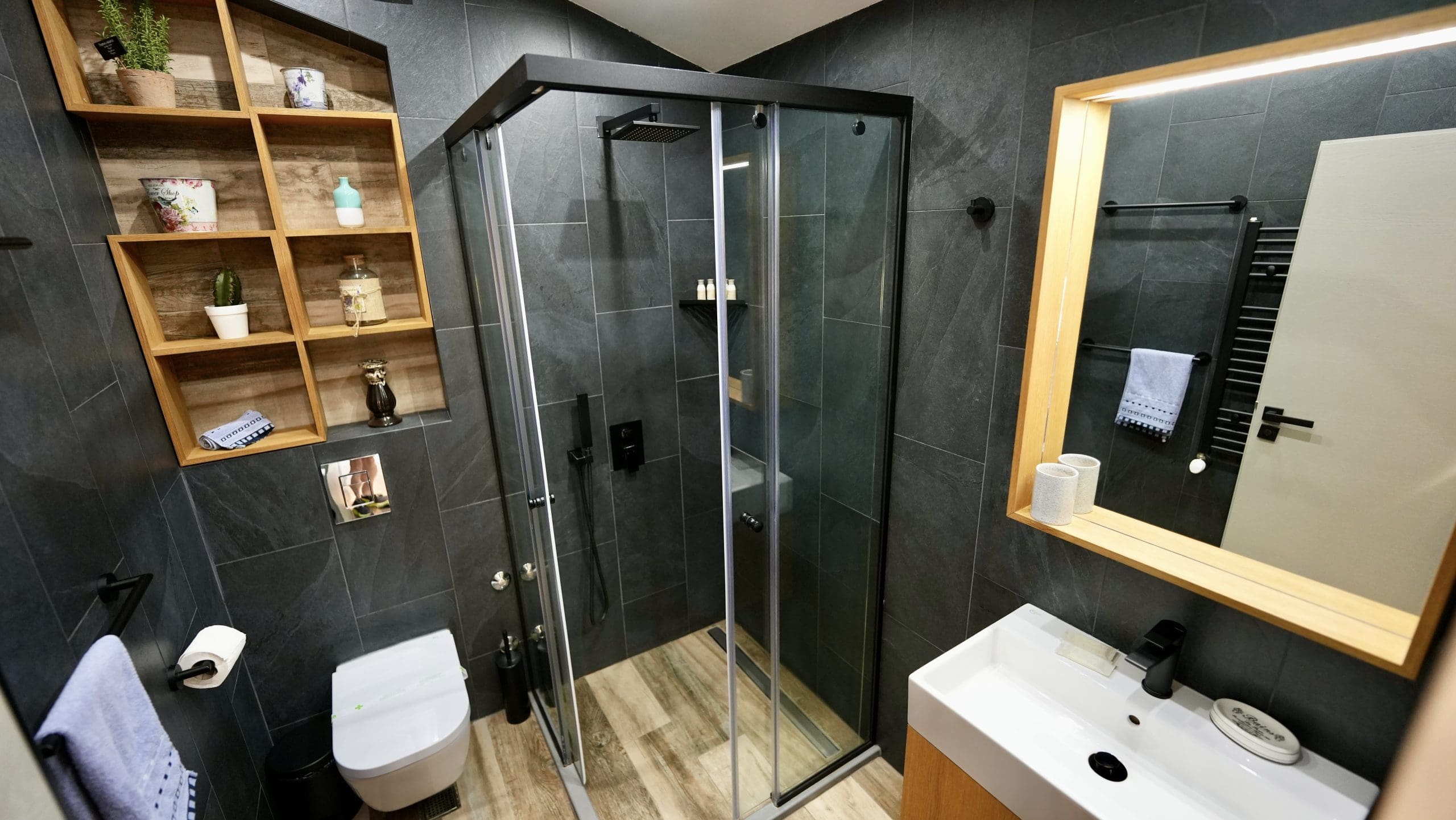 a bathroom with black tile shower and white sink
