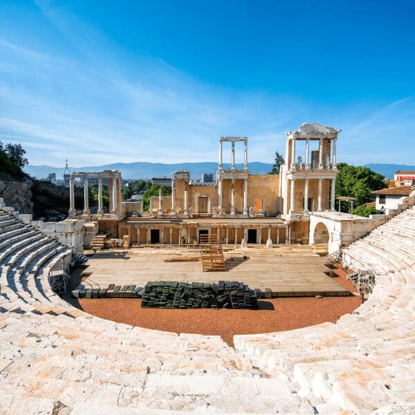 roman amphitheater with reddish marble seating and roman columns around stage