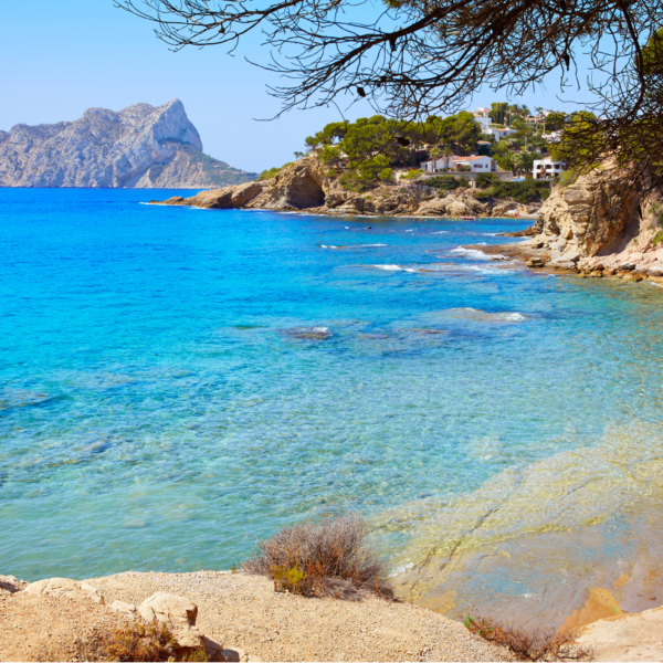 Cala Pinets Beach in Alicante, Spain with deep blue water and sandy beach.