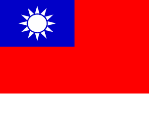 Red solid flag with upper left quadrant being bright blue with a white sun symbol inside. 