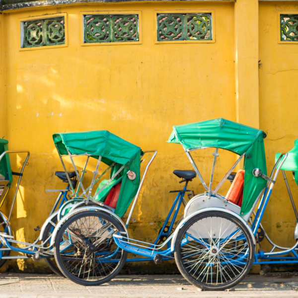 a yellow wall with green rickshaws lined up in a row