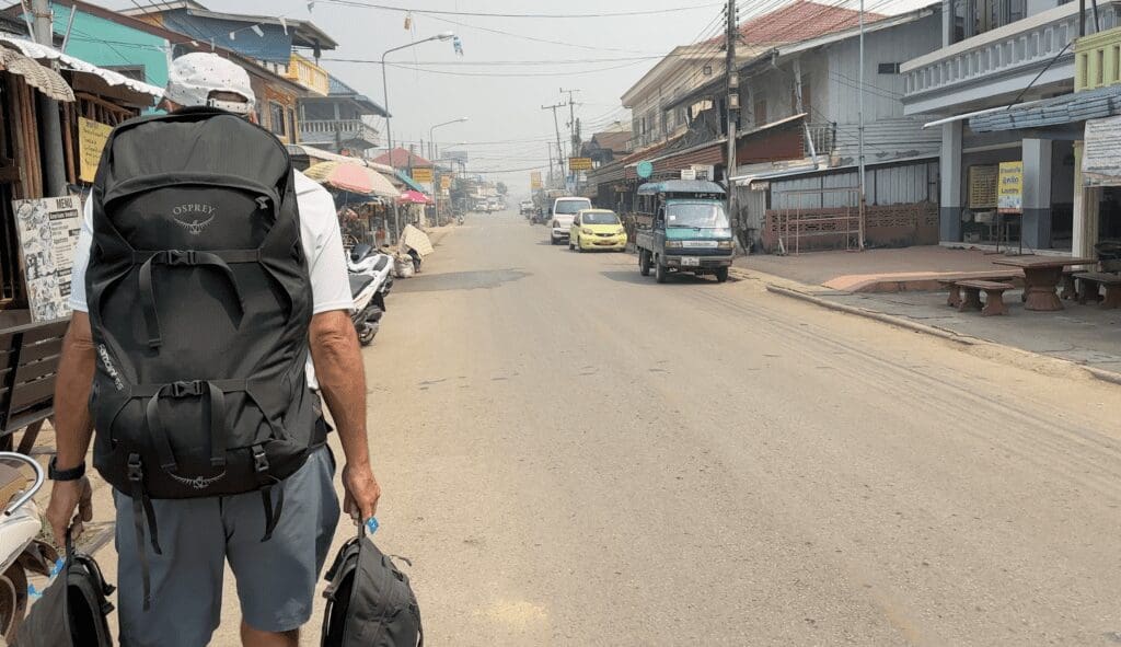 man walking with a backpack on a city street in Laos
