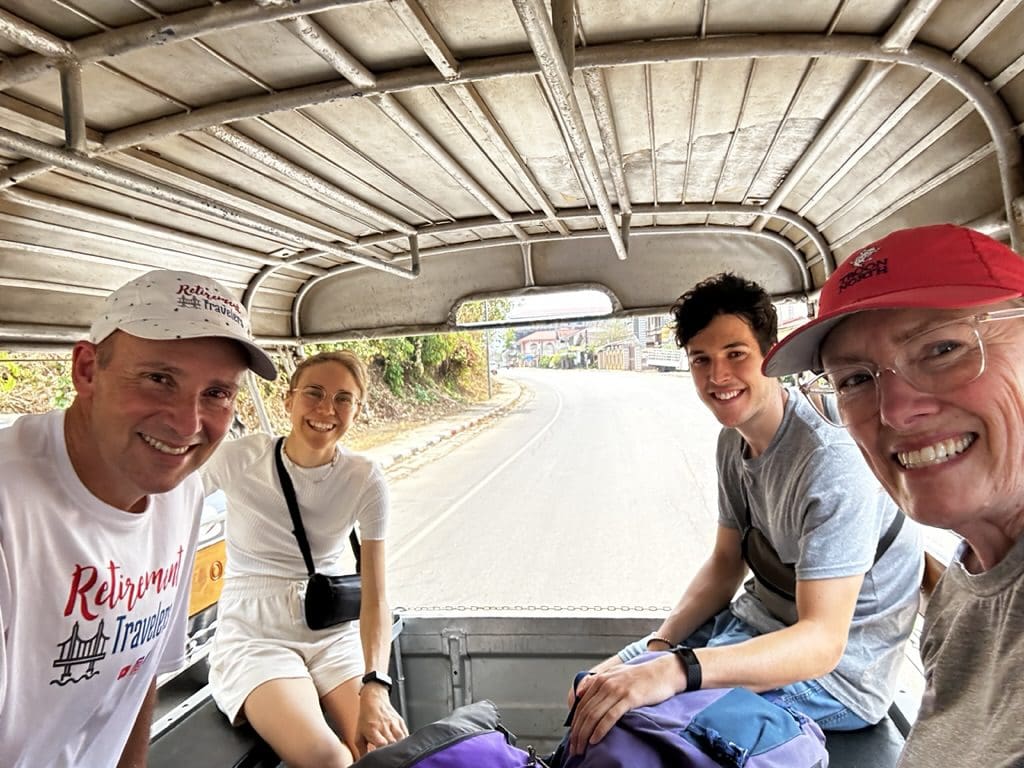 4 people riding in the back bed of small truck in Laos