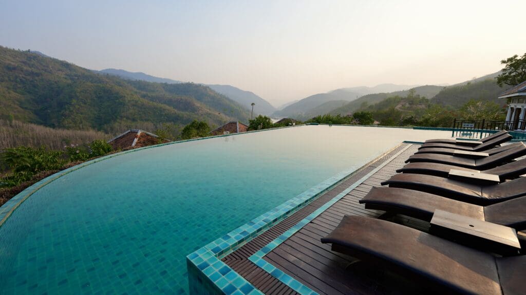 Infinity pool and seating at a hotel in Laos with views of mountains