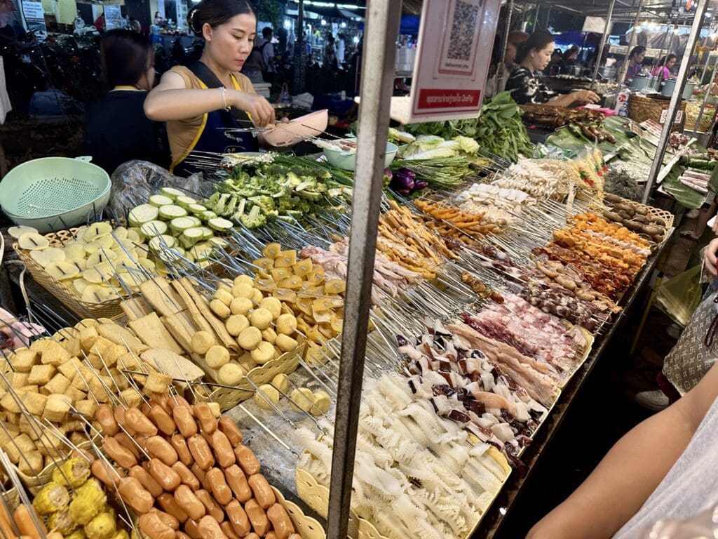 woman serving food at an outdoor Asian food market