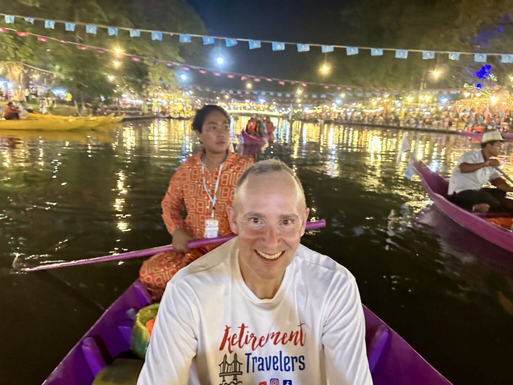 man in a purple boat with woman in orange clothing with paddle in a river surrounded by lights