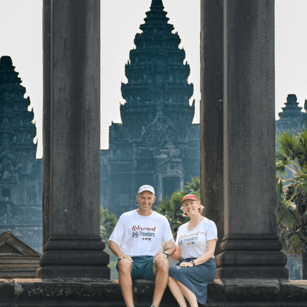 Retirement Travelers sitting in front of Angkor Wat temples in Cambodia