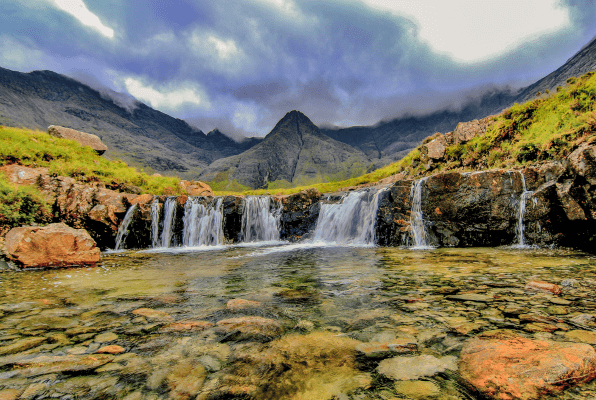 small waterfall in a fairy pool with mountains in the background in Scotland