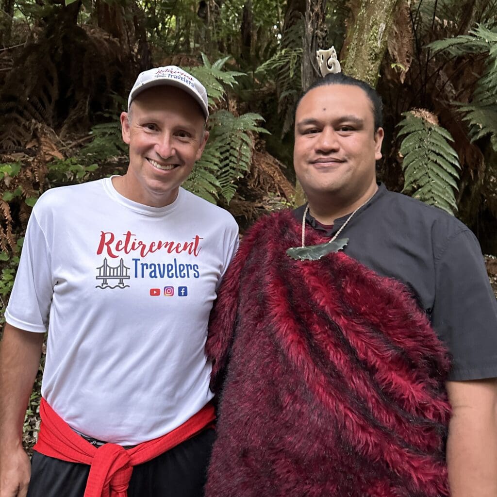 2 men standing beside each other, one wearing traditional Maori outfit