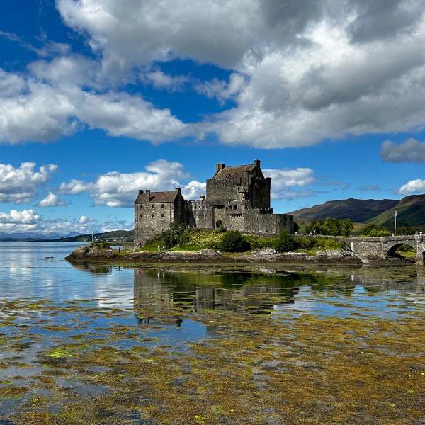 A view of the Castle at high tide with a blue cloudy sky.