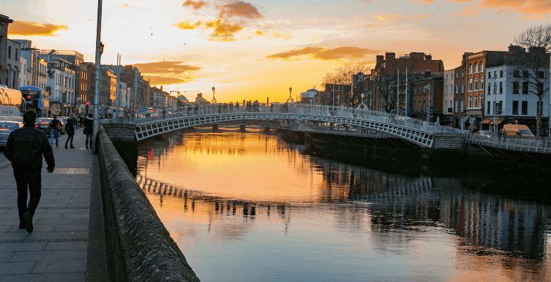 pedestrian bridge over a canal in Dublin Ireland at sunset with people walking along canal