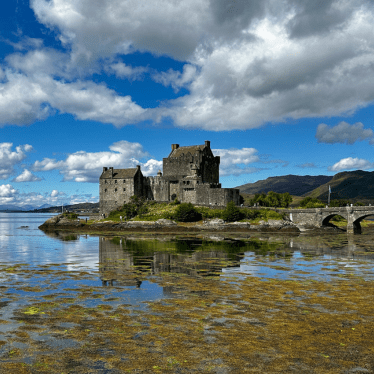 A view of the Castle at high tide with a blue cloudy sky.