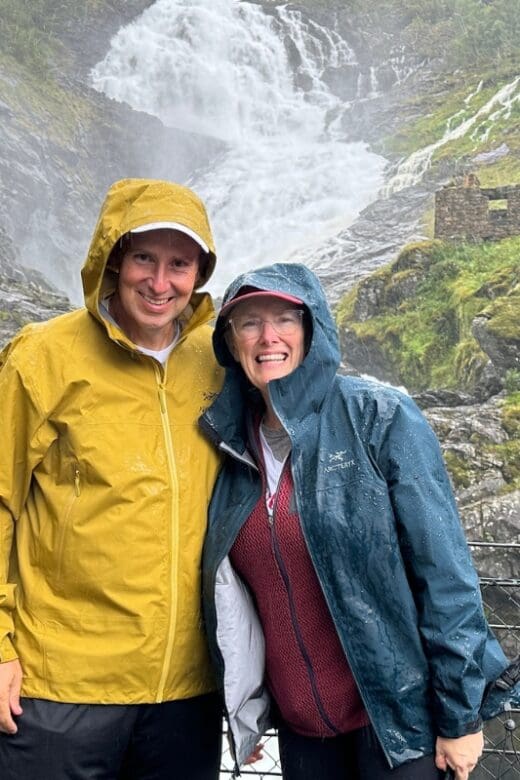 two people standing by a waterfall in Norway