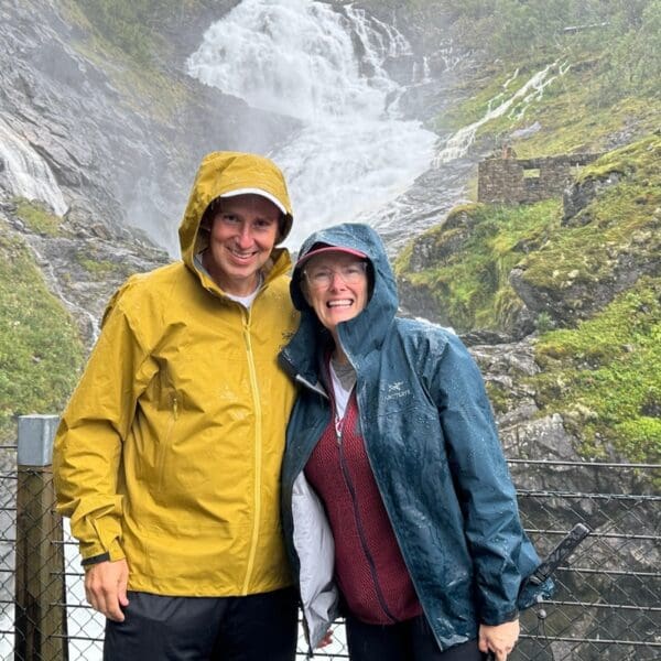 two people standing by a waterfall in Norway