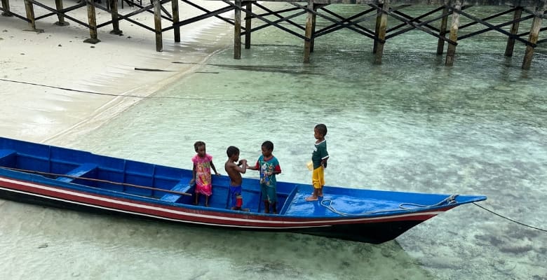4 children in a blue boat in raja ampat