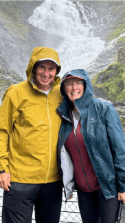 John and Bev posing in front of a waterfall in Norway.
