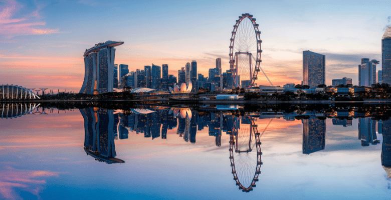 View of large Ferris wheel and buildings along a shoreline in Singapore