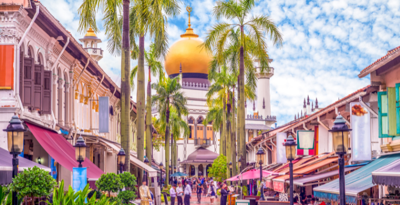 view of street lined with palm trees with gold temple in background in Singapore