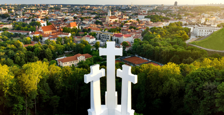 view of three adjacent white crosses on top of a hil overlooking city
