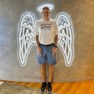 John standing by artwork giving him angels wings