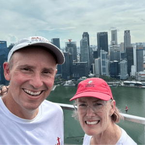 view of singapore from the top of the marina bay sands hotel with John and Bev in foreground