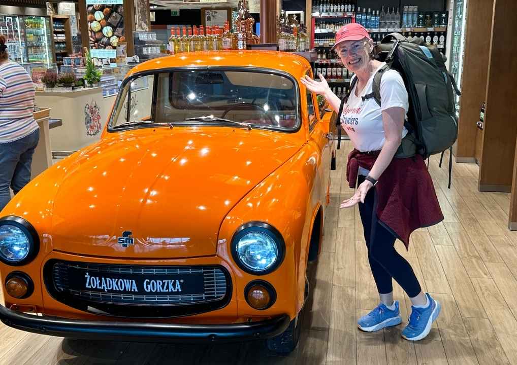 Bev standing by an orange car in the Warsaw airport
