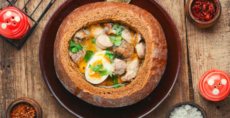 Bowl of Polish soup in a bread bowl on a plate