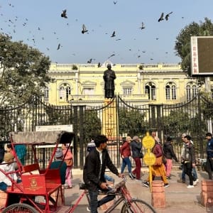 park with people and tuk tuks and statues in Delhi