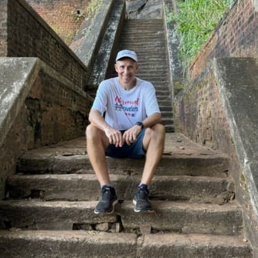 man sitting on steps of an ancient fortress in Sri Lanka