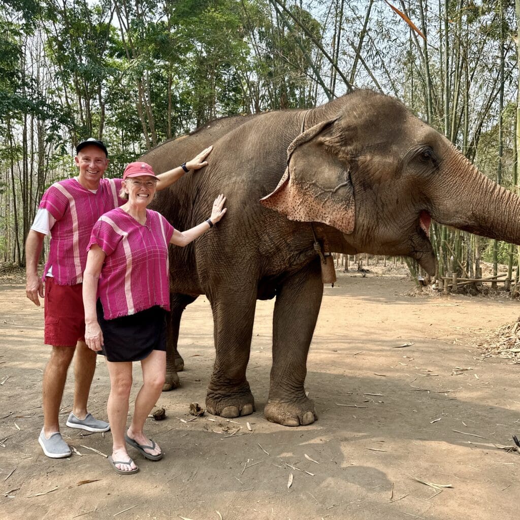 john and bev retirement travelers petting an elephant in Thailand