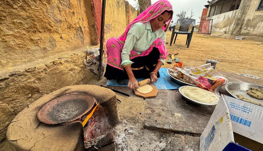 A woman cooking on the side of the street.