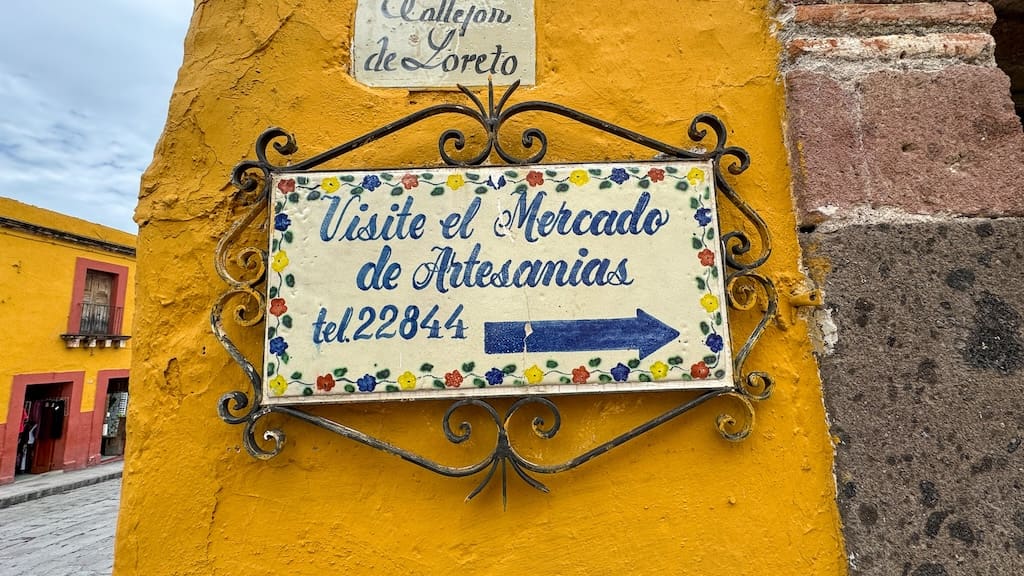 A Street sign with Mercado de Artesanias directions.