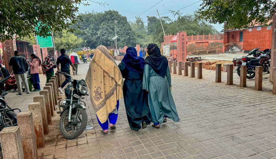 Women walking on the street dressed in long dresses with head scarfs.